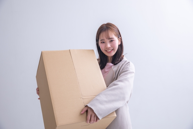 買取店へ直接売りたいグッズを段ボールに詰めて持って行くつもりの女性