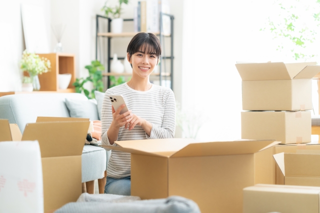 段ボールにアニメグッズを詰めようとしている女性のイメージ