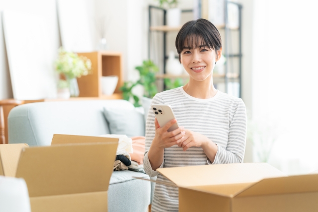 多忙な引っ越し前に宅配買取を使うためのスマホから店舗へ依頼している女性