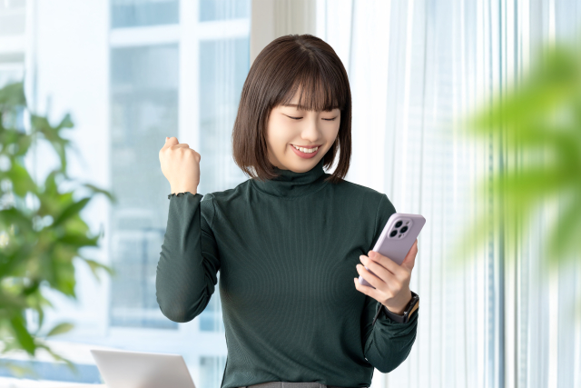 スマホをチェックしていると買取りしてもらおうと思っているアニメグッズ専門が金額アップキャンペーンをしていて喜ぶ女性
