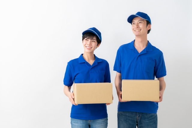 宅配業者の男性と女性が段ボールを持っている