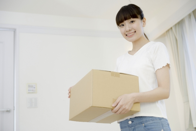 不要なグッズを段ボールに入れてトランクルームに預ける女性